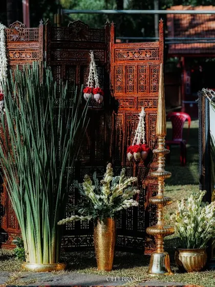 A warm, traditional welcome for wedding guests. This setup combines carved wooden screens, brass lamps, and fresh jasmine garlands to create an authentic and inviting entrance.