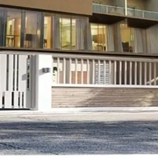 This view shows how the gate design complements the building's facade. The vertical lines of the gate and fence echo architectural elements of the home, creating a cohesive exterior design.