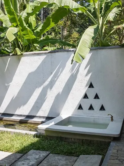 The private courtyard of the Garden Suite, featuring an outdoor bathtub and a lily pond set against a textured privacy wall.