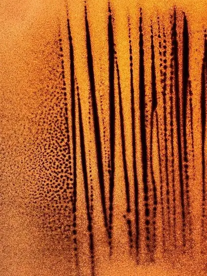 An untitled abstract work focusing on vertical lines and texture. The interplay between the fine, dotted sand and the stark black lines creates a sense of rhythm and depth.
