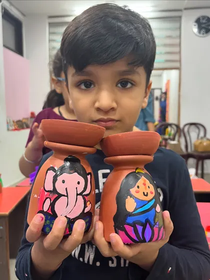 A student shows off the pair of tea-light holders he painted for Diwali.