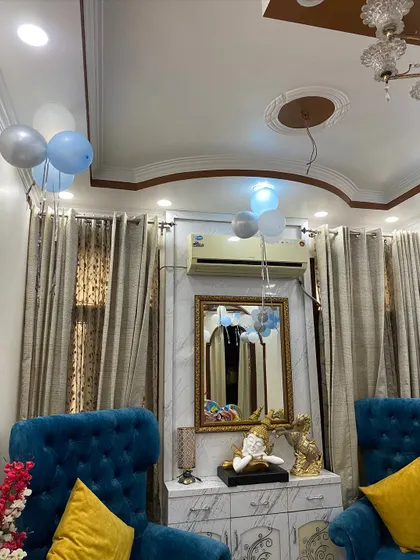 Simple and sweet home decoration for a baby's arrival, with bunches of blue, white, and silver balloons floating in the living room.