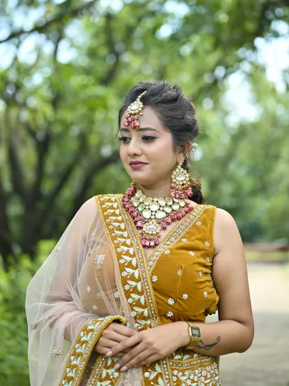 A three-quarter view of the mustard yellow lehenga, showing the intricate embroidery on the skirt and the matching pink-accented jewellery.