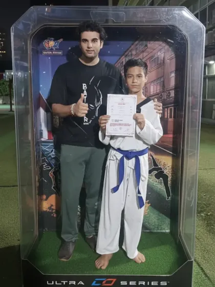 A student proudly displays his certificate after a successful belt grading. Each new belt is a milestone on the journey to black belt.
