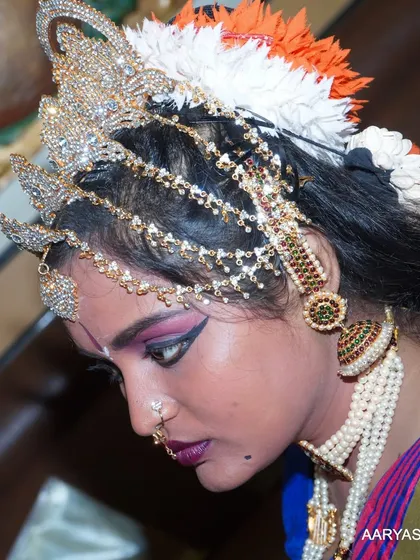 A side-profile close-up, highlighting the elaborate headwear and hairstyle of the classical dancer.