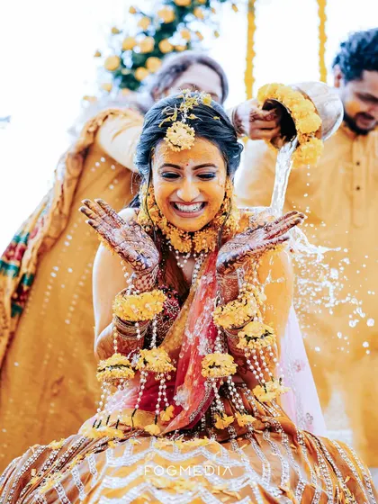 A joyful splash during the Haldi ritual. This action shot perfectly freezes a moment of fun and tradition, highlighting the bride's ecstatic expression.