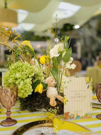 The centerpiece for each table was a work of art, featuring green hydrangeas, yellow tulips, and other fresh blooms, with a tiny crocheted teddy bear nestled within. The custom baby shower menu card completes the setting.