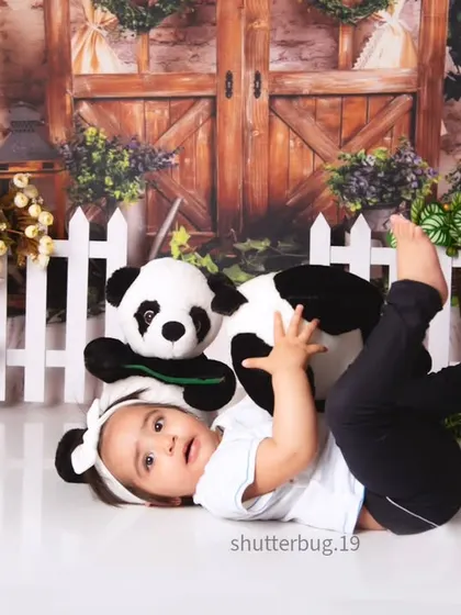 A playful moment as a baby lies on the floor with a stuffed panda during our garden panda theme shoot.