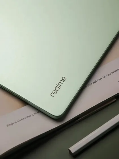 A flatlay of the realme Pad 2 on a green background, with a book and a cup of coffee, suggesting a relaxing reading experience.