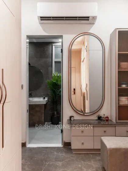 This view of the walk-in closet shows the integrated dressing table with an elegant oval mirror. The design ensures that every part of the space is utilized effectively, combining storage with a dedicated grooming area.