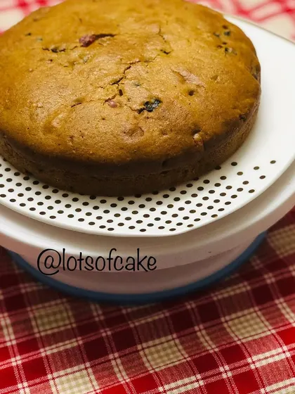The full eggless fruit cake before slicing, resting on a turntable. You can see the rich, dense texture of this non-alcoholic holiday bake.