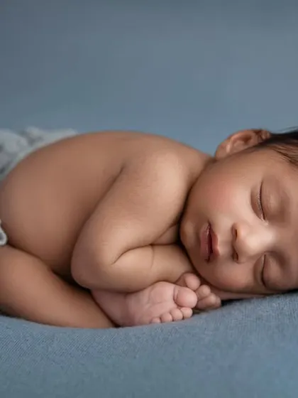 The 'taco' pose on a blue background, a perfect way to show how tiny and curled up newborns are.