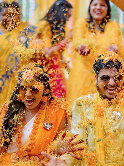 An explosion of marigold petals! This action shot captures the peak excitement and vibrant colors of the Haldi.