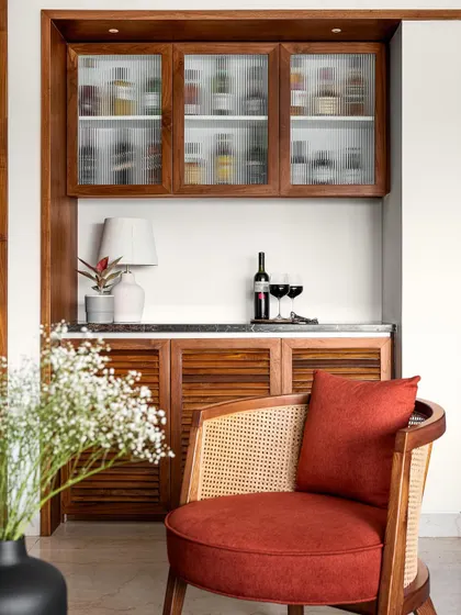 This compact bar unit is a beautiful blend of modern and traditional design, with louvered wooden shutters, a marble top, and fluted glass cabinets.