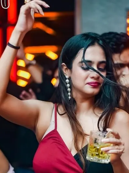 A dancer with a drink in hand, lost in the music and the moment.