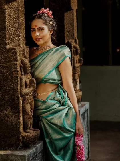 Another look from the 'Thamara' series, this time in a beautiful teal silk saree. The styling is inspired by temple statues, with a focus on the drape, traditional jewelry, and floral hair accents.