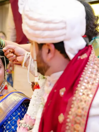 A close-up of a sacred ritual, where a family member blesses the couple, with the bride's hopeful gaze fixed on her groom.