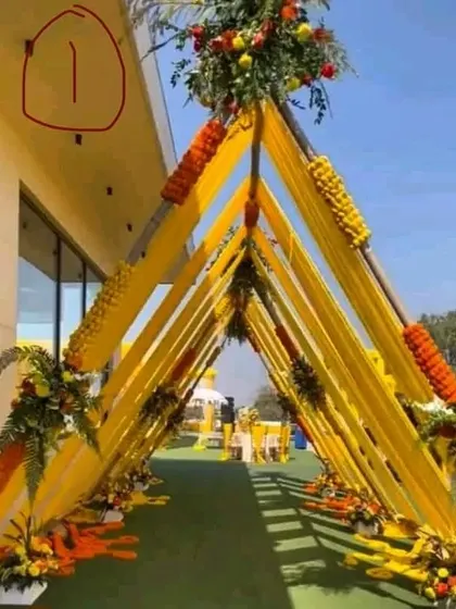 I design classic and welcoming entrances for Haldi ceremonies. This beautiful walkway tunnel is created with bright yellow drapes and traditional orange and yellow marigold flower arrangements, setting a perfect festive tone.
