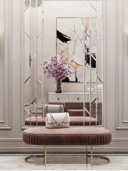 A chic entryway design with wall molding and a tall, segmented mirror. The plush pink bench adds a pop of color and a comfortable spot to sit.