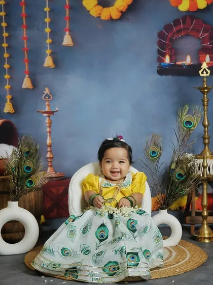 A beautiful little girl dressed in a peacock-feather-themed skirt for our Janmashtami shoot. Her smile truly lights up the photo.