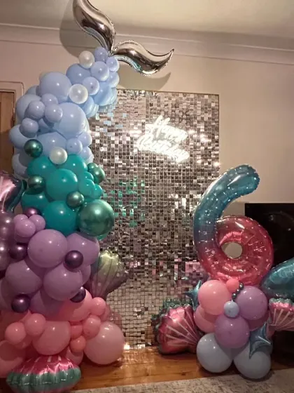 An intricate mermaid-themed balloon sculpture for a 6th birthday, featuring a shimmer wall and a large foil number balloon.