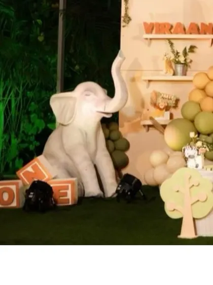A life-sized baby elephant prop sits beside 'ONE' blocks at our jungle-themed first birthday party. The surrounding greenery and earthy-toned balloons complete the immersive wild atmosphere.