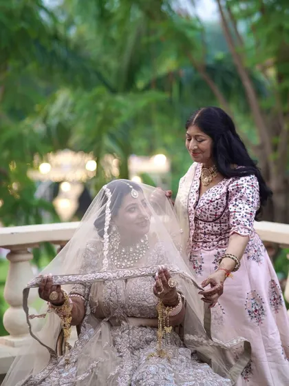 A mother or sister helps the bride with her veil, a touching and intimate moment.