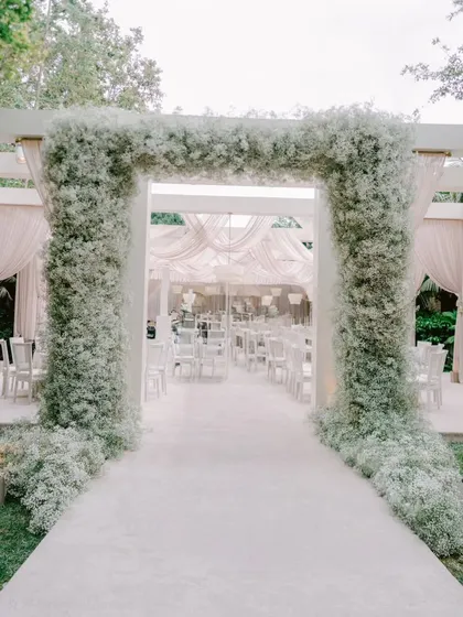An ethereal entrance crafted entirely from clouds of baby's breath. This design for an intimate gathering focused on creating a modern, monochromatic dreamscape, where clean lines and soft textures blend to feel both luxurious and calming.