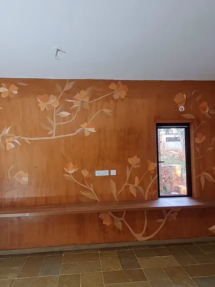 A beautiful floral branch mural that flows across a long wall, designed around a window and a built-in bench.