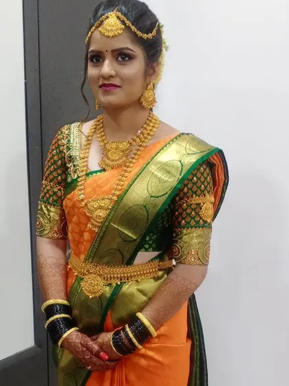 A full-length view of the bride's attire. You can see the expert saree draping and how the complete look, including the heavy black bangles and gold jewelry, comes together harmoniously.