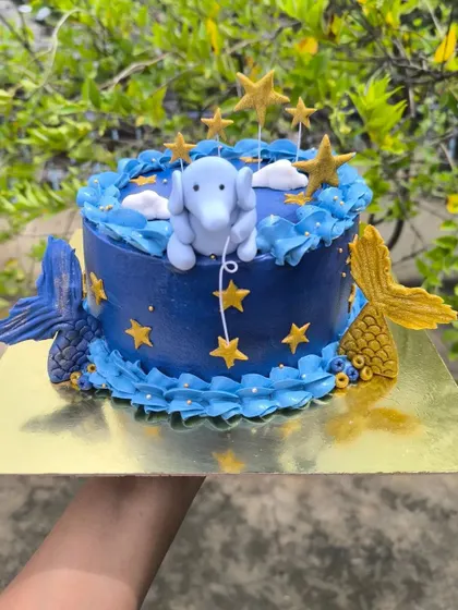 Mermaids, elephants, and galaxies. This cake brings comfort creatures and cosmic dreams to life, featuring a fondant elephant among the stars and mermaid tails diving into the cake.