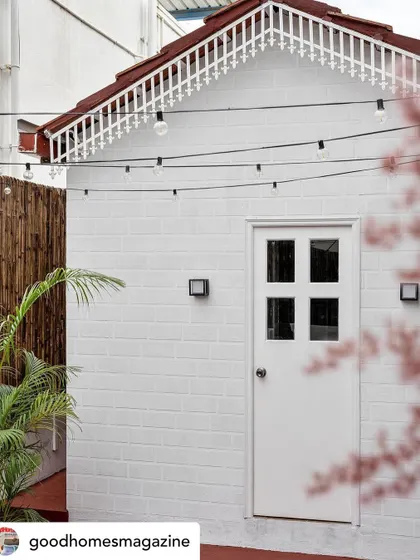The crafts shed in the backyard of 'Mina Nivas' is a charming, recreational studio for the client. The white brick, sloping roof, and festoon lights create a whimsical and inspiring space for creative explorations.