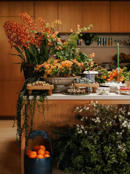 An indoor-outdoor food station overflowing with greenery and fresh flowers. The decor seamlessly connects the interior space with the garden outside.