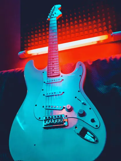 "Music is a necessity." An electric guitar bathed in neon light, capturing the energy and vibe of our academy.