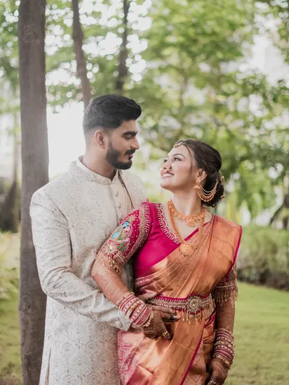 A happy couple portrait amidst nature. The bride's radiant smile and traditional attire shine in this beautiful outdoor setting.