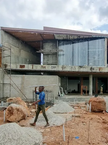 (Duplicate of 20) Another angle of House K under construction, showing the raw concrete form and the large boulders that are part of the site's natural landscape.