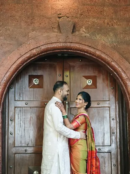 A candid glance between the couple, framed by the impressive architecture of a traditional Indian home, blending romance with heritage.