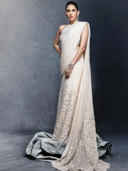 Pure elegance in this custom white draped saree by Tamara Ralph. The delicate floral embroidery and the dramatic train create a look that is both modern and timelessly graceful.
