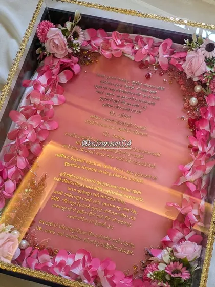 A wedding day is special, so the invitation should be too. This is a custom resin wedding invitation, or Kankotri, with the text in Gujarati font using a metal sticker. The 12x16 inch resin piece is presented in a beautiful box framed with artificial flowers.
