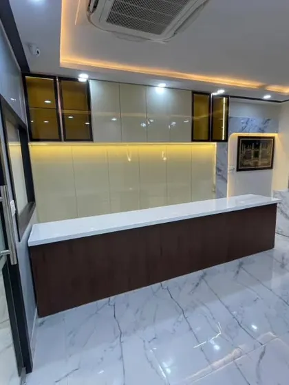 This is the reception area of a compact office space in Lucknow. I used glossy white marble floors, a dark wood reception desk, and backlit wall panels to create a sense of luxury and space.