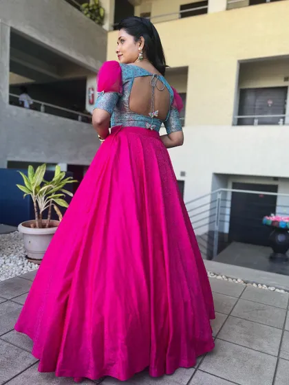 The back view of the blue and pink lehenga, showcasing the stylish cutout back of the blouse and the vibrant pink skirt.