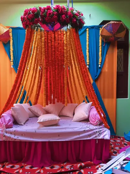 This is the kind of Haldi setup I love to create. I used bright blue and orange drapes for the backdrop, with a canopy of fresh marigold garlands and a beautiful red rose arrangement on top. The seating is perfect for photos, making your special day even more memorable.
