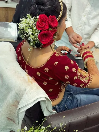 Our artist carefully applying nail polish to match the bride's outfit, while her beautiful floral bun is already complete. We take care of all the small details.
