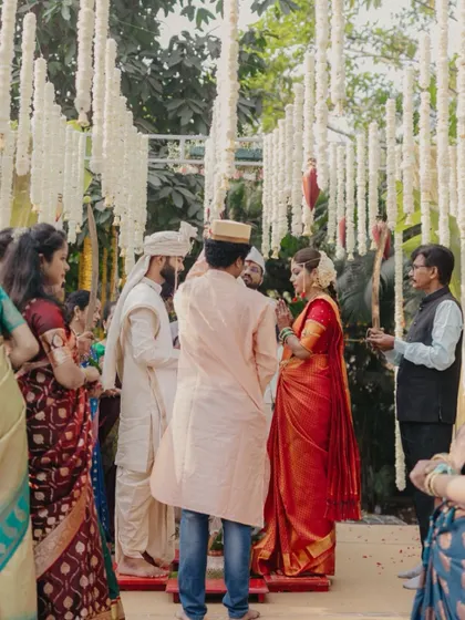 A candid shot of the wedding ceremony in progress, capturing the guests and priests surrounding the couple.