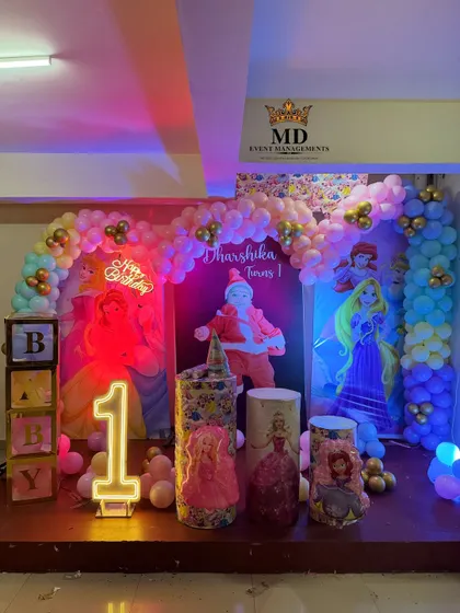 The Disney Princess stage decoration illuminated with colorful party lights, showing how the setup looks during the event. The neon signs and character backdrops create a magical atmosphere.