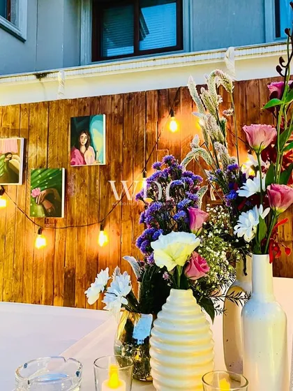 A personal touch. A wooden wall is decorated with the birthday girl's portraits and strings of Edison bulbs, creating a warm and nostalgic gallery.