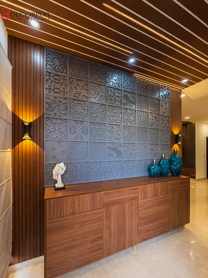 A wide shot of the artistic foyer unit, showing its placement in the home's entryway. The wall sconces provide warm, ambient lighting that highlights the intricate details of the CNC panel.