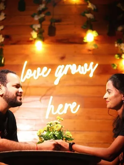 A pre-wedding shoot in a cafe setting with a "love grows here" neon sign. We can create a theme around your story, like a cozy coffee shop where your love blossomed.