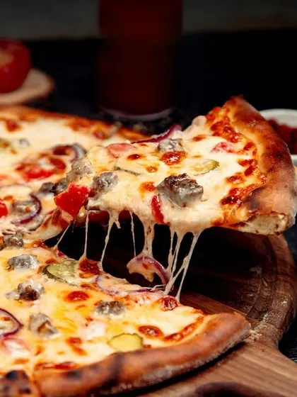 A cheesy slice of our freshly baked pizza, with that perfect cheese pull.