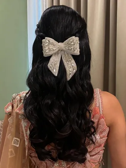 A chic and modern half-up style with soft waves, finished with a large, embellished bow accessory.